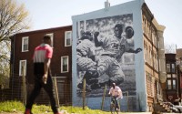 People pass by a Philadelphia Mural Arts Program mural of Jackie Robinson in Philadelphia on Friday, April 15, 2016. On Jackie Robinson Day, Philadelphia is acknowledged its racist treatment of the baseball pioneer when he played in the city nearly 70 years ago. City leaders issued an official apology in March, and highlighted its official apology during a ceremony Friday, also honoring Moses Fleetwood Walker, the first black Major League player. (AP Photo/Matt Rourke)