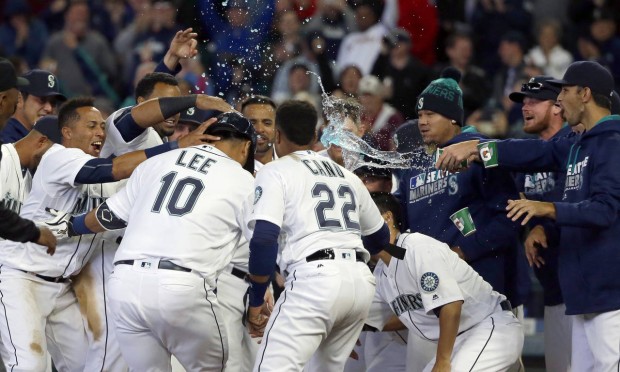 Seattle Mariners' Dae-Ho Lee (10) is greeted at the plate by teammates after he hit a walk-off two-run home run in the 10th inning of a baseball game against the Texas Rangers, Wednesday, April 13, 2016, in Seattle. The Mariners won 4-2. (AP Photo/Ted S. Warren)