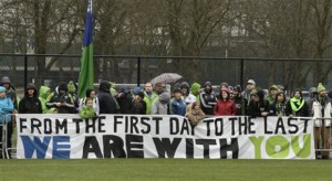 Seattle Sounders supporters stand behind a large sign Saturday, Jan. 23, 2016, as they watch MLS soccer training in Tukwila, Wash. (AP)
