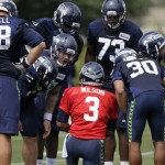 Seattle Seahawks quarterback Russell Wilson (3) gives directions inside a huddle during the team's NFL football training camp Saturday, July 30, 2016, in Renton, Wash. (AP Photo/Elaine Thompson)