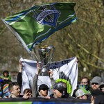 Members of the Emerald City Supporters hold up smoke effects as they take part in the traditional March to the Match with the 2016 MLS Cup trophy before an MLS soccer match between the Seattle Sounders and the New York Red Bulls, Sunday, March 19, 2017, in Seattle. (AP Photo/Ted S. Warren)