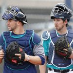 Seattle Mariners catchers Mike Zunino, left, and Joe Odom, right, watch a drill during a baseball spring training workout, Monday, Feb. 19, 2018, in Peoria, Ariz. (AP Photo/Charlie Neibergall)