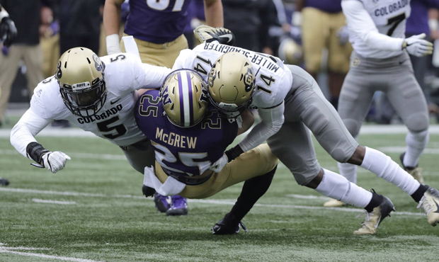 Washington tailback Sean McGrew (25) is tackled by Colorado's Davion Taylor, left, and Chris Miller...