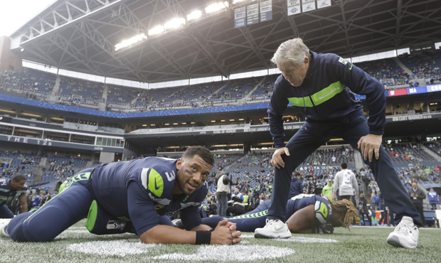 Seattle Seahawks quarterback Russell Wilson, left, talks with head coach Pete Carroll as he stretch...