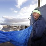 Former Seattle Seahawks player Lawyer Milloy gives out a yell as he gets ready to raise a "12 Flag," a show of support of Seahawks' fans, atop the Space Needle Friday, Jan. 4, 2019, in Seattle. The flag will fly in celebration of the team's wild card playoff game in Dallas on Saturday against the Cowboys and will remain up through Sunday, Jan. 6. (AP Photo/Elaine Thompson)
