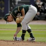 
              Oakland Athletics starting pitcher Daniel Mengden cleans mud off his shoes as he throws during the first inning of a spring training baseball game against the Seattle Mariners, Friday, Feb. 22, 2019, in Peoria, Ariz. (AP Photo/Charlie Riedel)
            