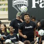Seattle Seahawks NFL football quarterback Russell Wilson heads a soccer ball, Monday, Aug. 19, 2019, during an event in Seattle held to introduce Wilson, his wife, pop singer Ciara, hip-hop artist Macklemore, and others as new members of the Seattle Sounders MLS soccer team's ownership group. (AP Photo/Ted S. Warren)