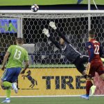 Real Salt Lake goalkeeper Nick Rimando, center, leaps as a shot goes wide and Seattle Sounders forward Jordan Morris, left, and Real Salt Lake defender Aaron Herrera, right, watch during the first half of an MLS Western Conference semifinal playoff soccer match Wednesday, Oct. 23, 2019, in Seattle. (AP Photo/Ted S. Warren)
