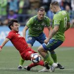 Toronto FC's Tsubasa Endoh, left, battles for a ball with Seattle Sounders' Jordan Morris, right, Sunday, Nov. 10, 2019, during the first half of the MLS Cup championship soccer match in Seattle. (AP Photo/Elaine Thompson)