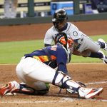 HOUSTON, TEXAS - JULY 26: Shed Long Jr. #4 of the Seattle Mariners scores on a single by Kyle Lewis #1 in the eighth inning as Martin Maldonado #15 of the Houston Astros is late with the tag at Minute Maid Park on July 26, 2020 in Houston, Texas.  (Photo by Bob Levey/Getty Images)