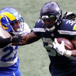 SEATTLE, WASHINGTON - JANUARY 09: Running back Chris Carson #32 of the Seattle Seahawks carries the football against cornerback Troy Hill #22 of the Los Angeles Rams during the first quarter of the the NFC Wild Card Playoff game at Lumen Field on January 09, 2021 in Seattle, Washington. (Photo by Steph Chambers/Getty Images)