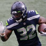 SEATTLE, WASHINGTON - JANUARY 09: Running back Chris Carson #32 of the Seattle Seahawks carries the football against the defense of the Los Angeles Rams during the first quarter of the the NFC Wild Card Playoff game at Lumen Field on January 09, 2021 in Seattle, Washington. (Photo by Steph Chambers/Getty Images)