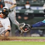 SEATTLE, WASHINGTON - APRIL 02: Donovan Solano #7 of the San Francisco Giants slides safely past Luis Torrens #22 of the Seattle Mariners in the seventh inning at T-Mobile Park on April 02, 2021 in Seattle, Washington. (Photo by Steph Chambers/Getty Images)