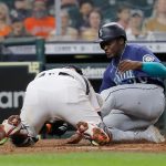 HOUSTON, TEXAS - APRIL 28: Taylor Trammell #20 of the Seattle Mariners slides safely into home base against Martin Maldonado #15 of the Houston Astros in the fourth inning at Minute Maid Park on April 28, 2021 in Houston, Texas. (Photo by Bob Levey/Getty Images)
