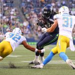SEATTLE, WASHINGTON - AUGUST 28: Alex Collins #41 of the Seattle Seahawks is tackled by Alohi Gilman #32 and Nick Niemann #31 of the Los Angeles Chargers in the first quarter during the NFL preseason game at Lumen Field on August 28, 2021 in Seattle, Washington. (Photo by Abbie Parr/Getty Images)