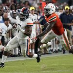 
              Virginia Cavaliers running back Mike Hollins (7) runs ahead of Miami Hurricanes safety James Williams for a touchdown during the first half of a NCAA college football game, Thursday, Sept. 30, 2021, in Miami Gardens, Fla. (AP Photo/Lynne Sladky)
            