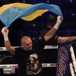 
              Oleksandr Usyk of Ukraine holds up the Ukrainian flag after his unanimous decision victory over Anthony Joshua of Britain in their WBA (Super), WBO and IBF boxing title bout at the Tottenham Hotspur Stadium in London, Saturday, Sept. 25, 2021. (AP Photo/Frank Augstein)
            