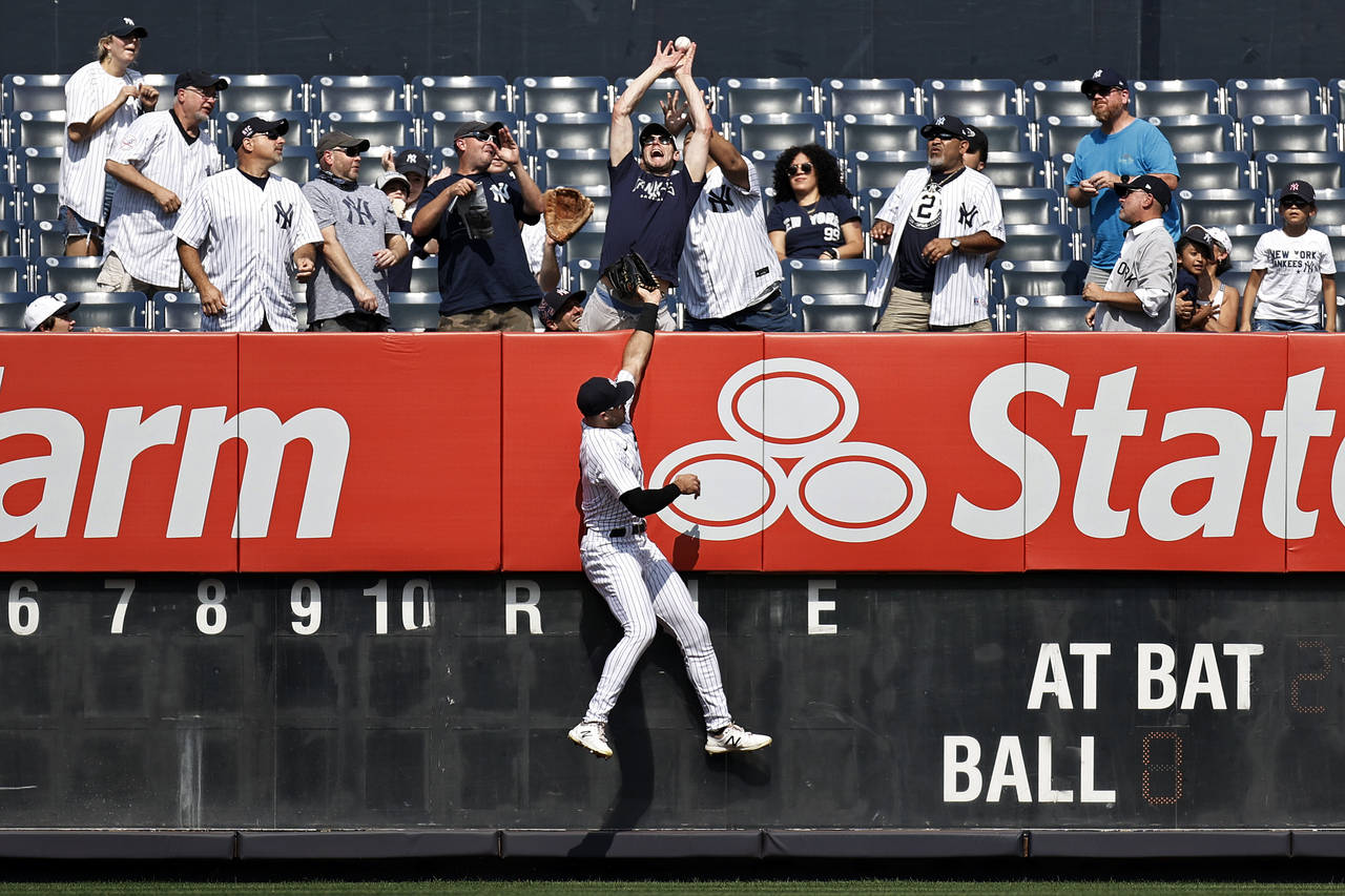 New York Yankees left fielder Joey Gallo jumps at the wall as a fan attempts to catch a two-run hom...