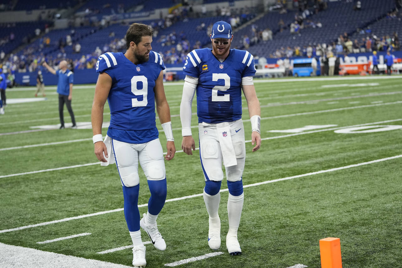 Indianapolis Colts quarterback Carson Wentz (2) walks off the filed with quarterback Jacob Eason (9...