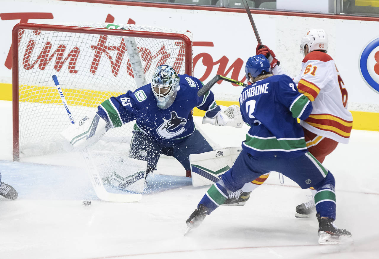 Vancouver Canucks goalie Michael DiPietro (65) stops Calgary Flames' Walker Duehr (61) as Canucks' ...