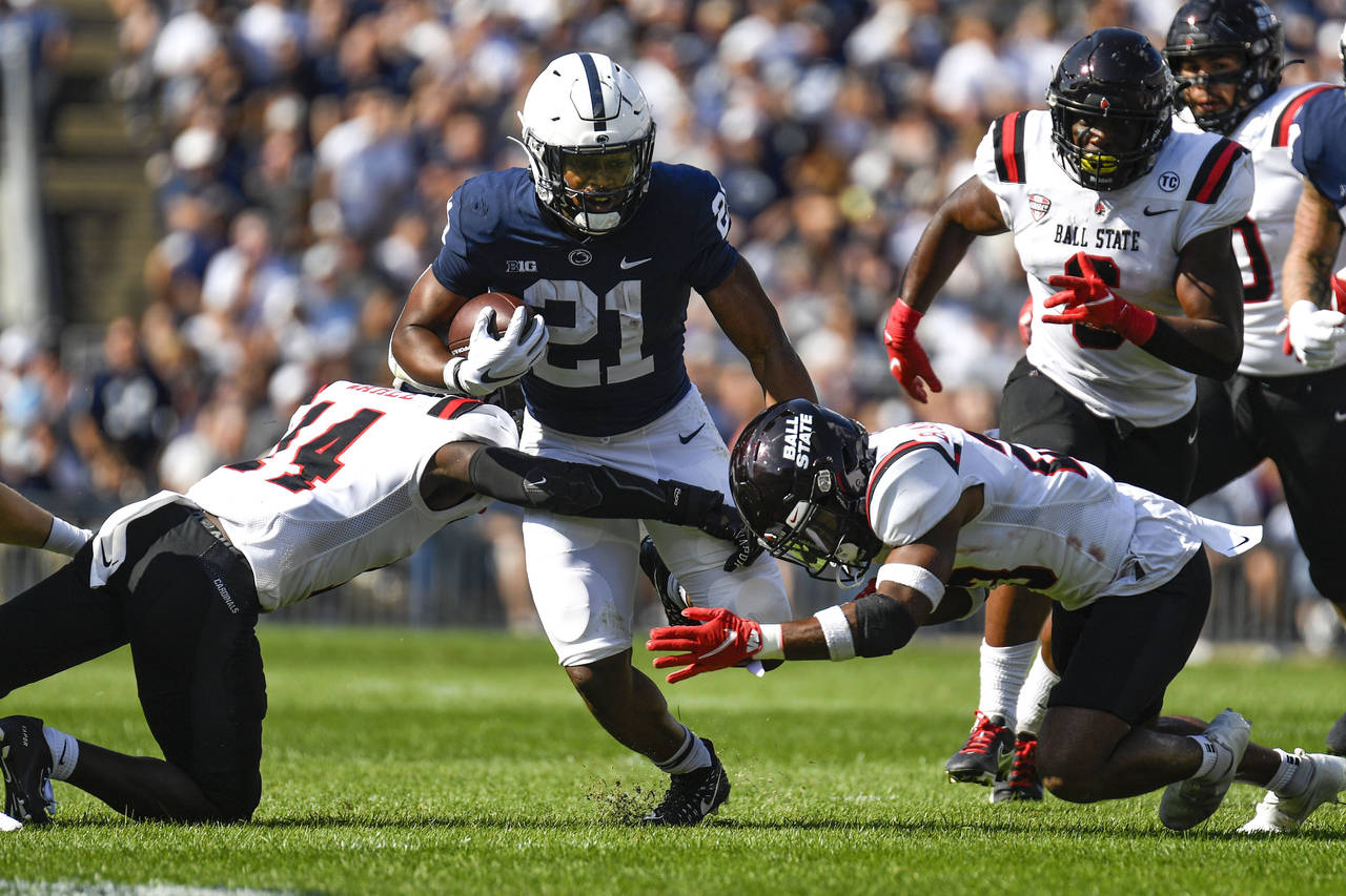 Penn State running back Noah Cain (21) splits two Ball State defenders on a first half run during a...