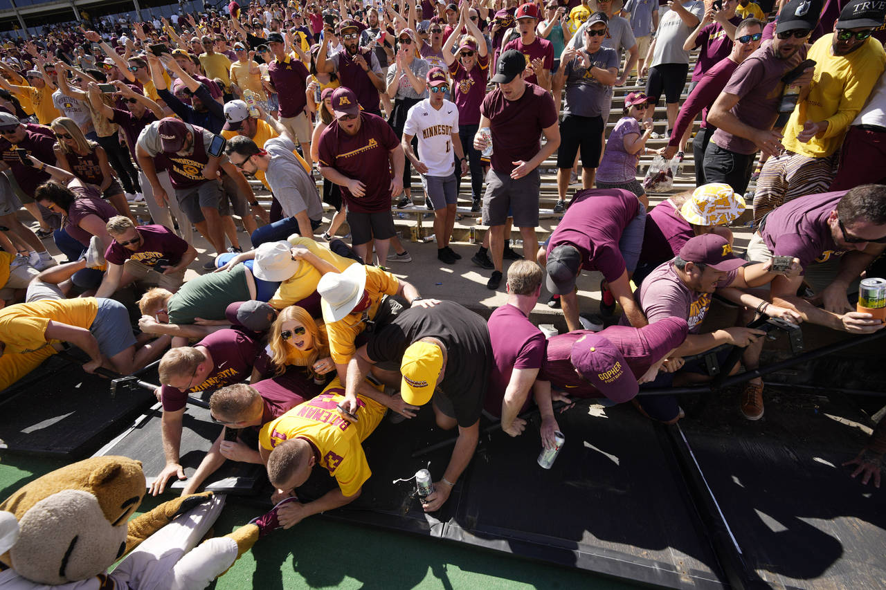 Minnesota fans collapse the fence around the field while congratulating players after the second ha...