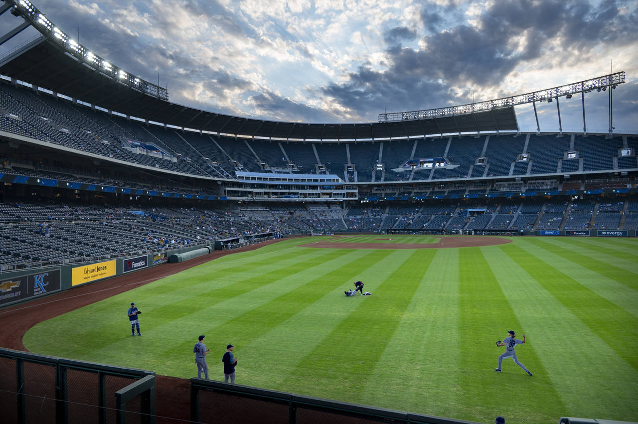Kansas City Royals starting pitcher Jackson Kowar, lower right, warms up in the outfield before the...