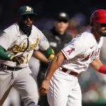 
              Oakland Athletics' Josh Harrison, background left, chases Los Angeles Angels' Jack Mayfield to tag him out during the 10th inning of a baseball game Sunday, Sept. 19, 2021, in Anaheim, Calif. (AP Photo/Jae C. Hong)
            