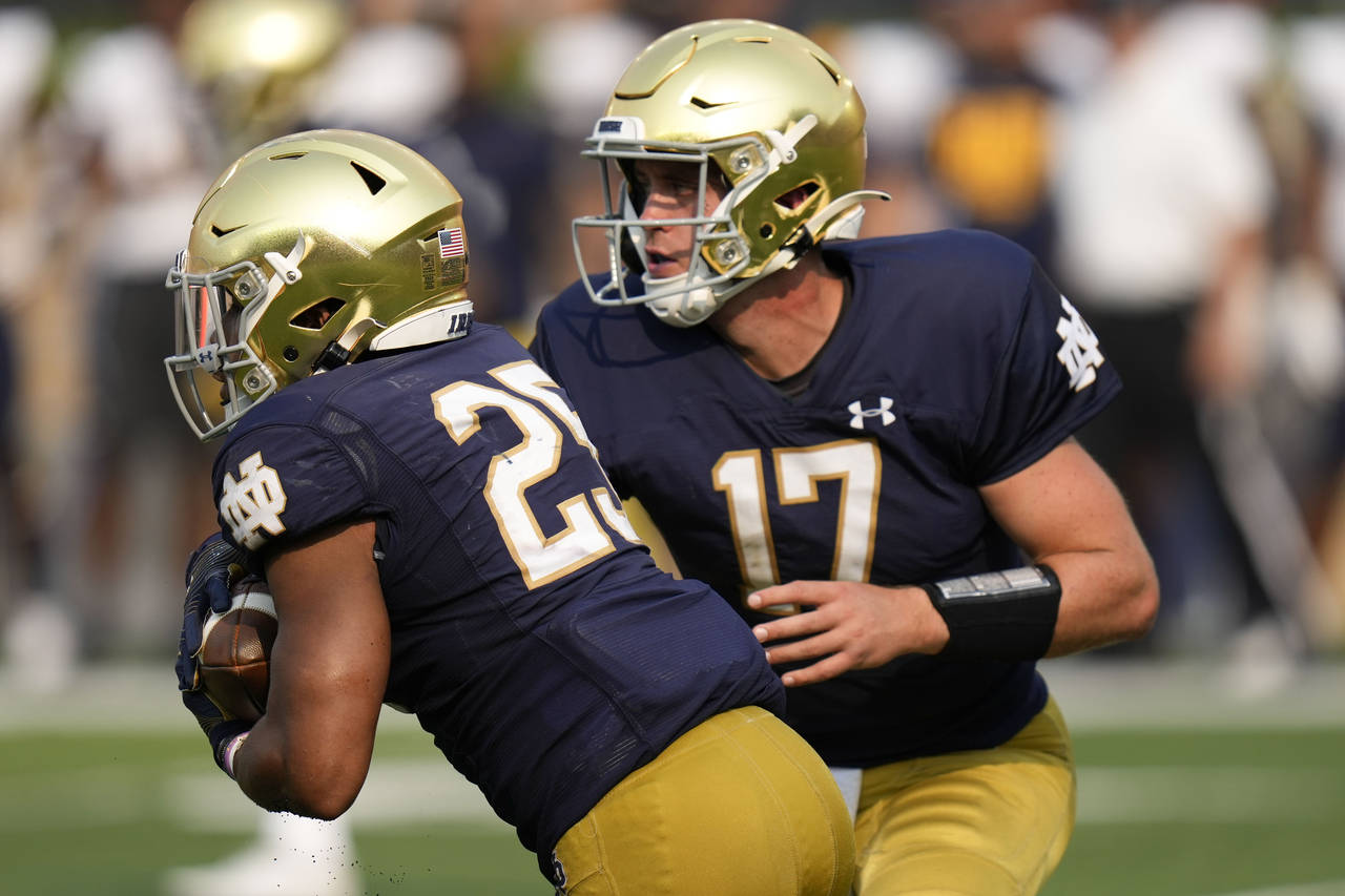 Notre Dame quarterback Jack Coan (17) hands off to running back Chris Tyree (25) in the second half...