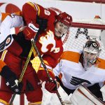 
              Philadelphia Flyers' Rasmus Ristolainen, left, battles with Calgary Flames' Matthew Tkachuk in front of Flyers goalie Carter Hart
            