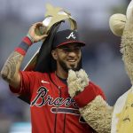 
              Atlanta Braves left fielder Eddie Rosario removes a crown hat from his head beside Braves mascot 'Blooper' prior to a baseball game against the New York Mets, Friday, Oct. 1, 2021, in Atlanta. (AP Photo/Ben Margot)
            
