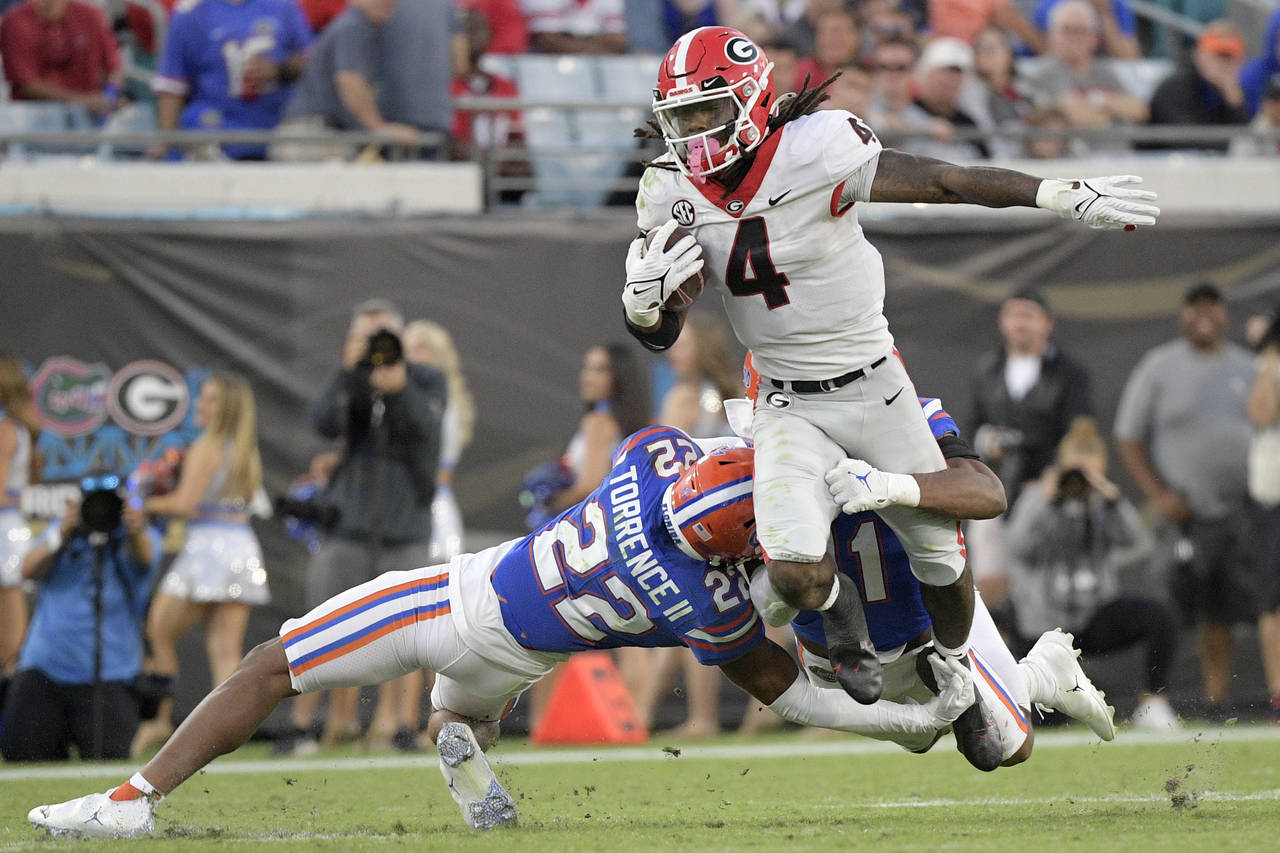 Georgia running back James Cook (4) is tackled by Florida safety Rashad Torrence II (22) and lineba...