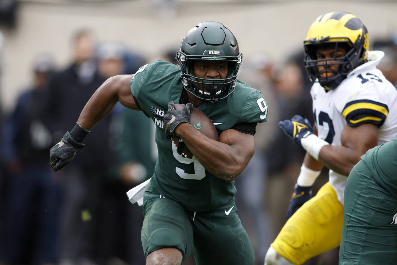 Michigan State's Kenneth Walker III (9) rushes against Michigan's Josh Ross during the first quarte...