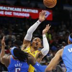
              Los Angeles Lakers' Russell Westbrook (0) passes the ball away from Oklahoma City Thunder forward Luguentz Dort (5) and forward Darius Bazley (7) during the first half of an NBA basketball game, Wednesday, Oct. 27, 2021, in Oklahoma City. (AP Photo/Garett Fisbeck)
            