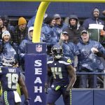 
              Fans, background, cheer as Seattle Seahawks' DK Metcalf (14) tosses aside the ball after scoring on an 84-yard pass play against the New Orleans Saints during the first half of an NFL football game, Monday, Oct. 25, 2021, in Seattle. (AP Photo/Ted S. Warren)
            