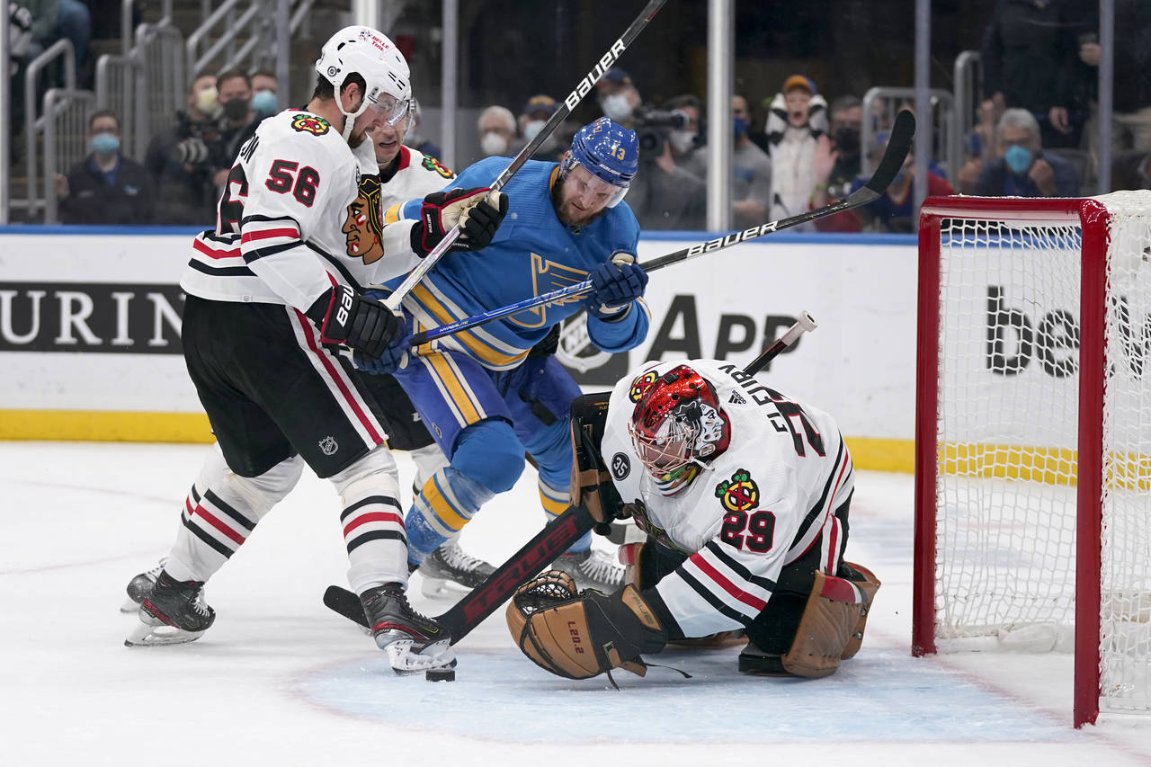 St. Louis Blues' Kyle Clifford (13) keeps is eye on a loose puck as Chicago Blackhawks goaltender M...