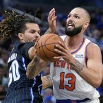 
              New York Knicks' Evan Fournier (13) goes up for a shot against Orlando Magic's Cole Anthony, left, during the first half of an NBA basketball game Friday, Oct. 22, 2021, in Orlando, Fla. (AP Photo/John Raoux)
            