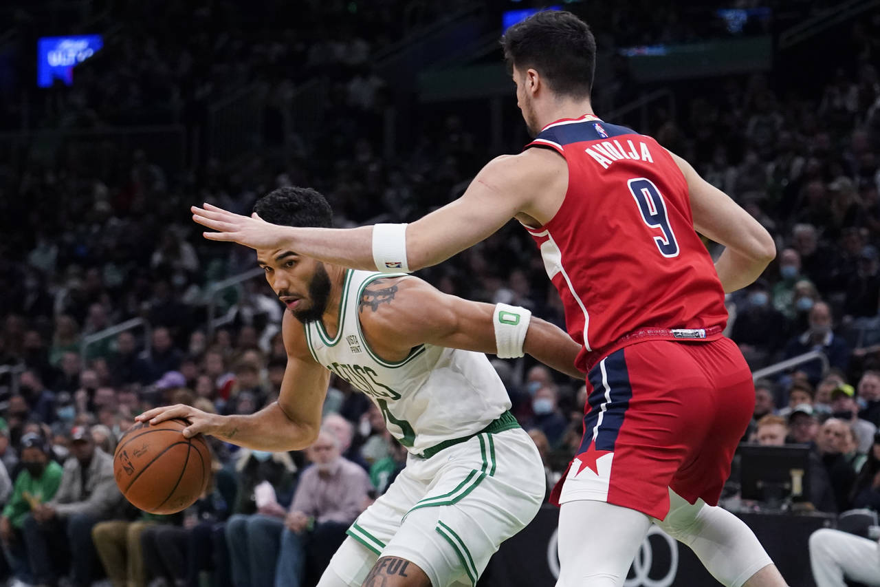 Boston Celtics forward Jayson Tatum (0) tries to drive past Washington Wizards forward Deni Avdija ...