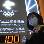 
              A supporter makes a gesture with her hands near a countdown clock as it crosses into the 100 days countdown to the opening of the Winter Olympics in Beijing, China, Tuesday, Oct. 26, 2021. (AP Photo/Ng Han Guan)
            