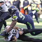 
              Seattle Seahawks' Rasheem Green tumbles across Jacksonville Jaguars quarterback Trevor Lawrence after Lawrence kept the ball on a carry during the second half of an NFL football game, Sunday, Oct. 31, 2021, in Seattle. (AP Photo/Ted S. Warren)
            