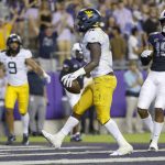 
              West Virginia running back Leddie Brown (4) reacts after running the ball into the end zone for a touchdown as TCU safety Josh Foster (15) looks on during the first half of an NCAA college football game Saturday, Oct. 23, 2021, in Fort Worth, Texas. (AP Photo/Ron Jenkins)
            