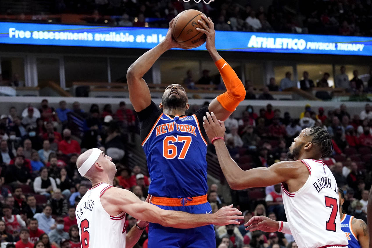 New York Knicks center Taj Gibson, center, rebounds the ball against Chicago Bulls guard Alex Carus...