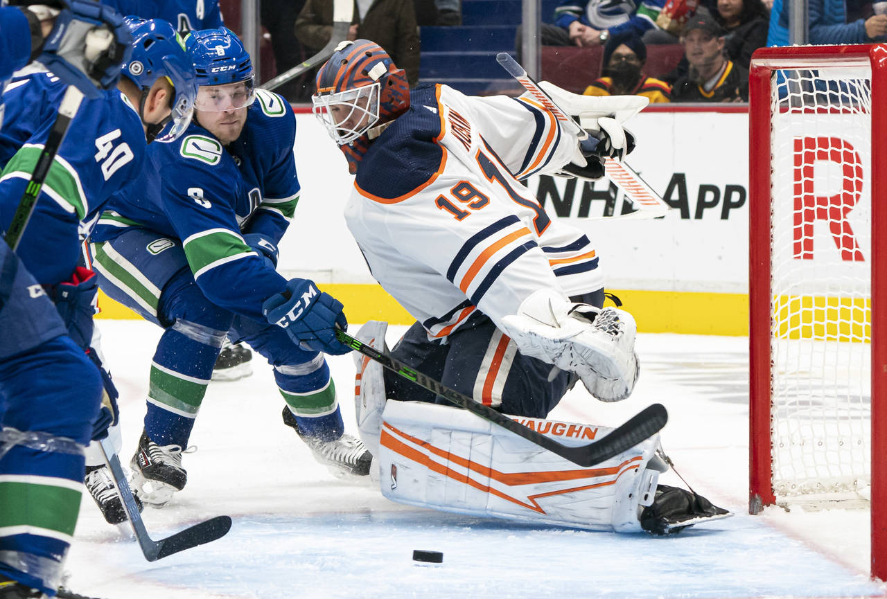 Vancouver Canucks' Brock Boeser, left, loses control of the puck as Edmonton Oilers goalie Mikko Ko...