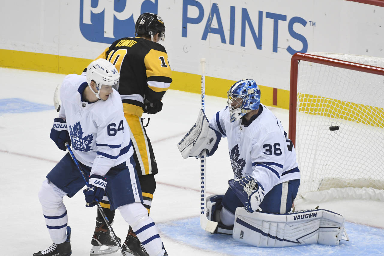 Toronto Maple Leafs' David Kampf (64) and Pittsburgh Penguins' Drew O'Connor (10) watch a puck get ...