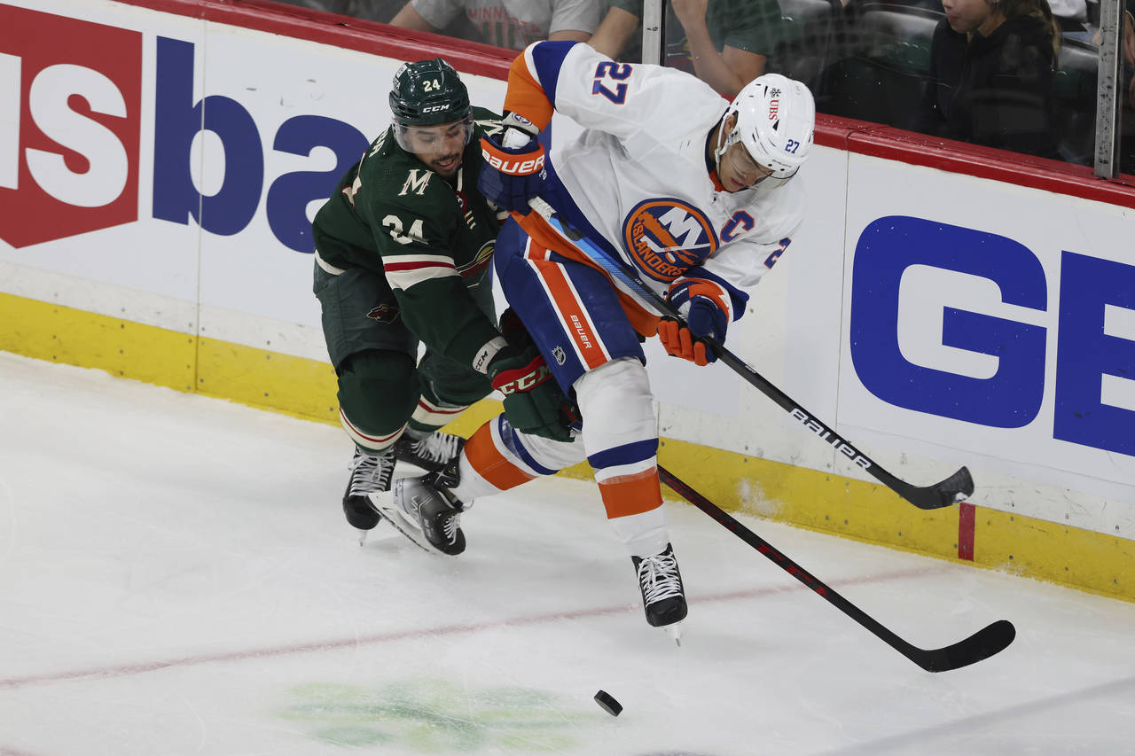 New York Islanders' Anders Lee (27) and Minnesota Wild's Matt Dumba (24) go after the puck during t...