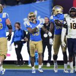 
              UCLA running back Kazmeir Allen, center, tosses the ball as he walks past California linebacker Cameron Goode, right, after scoring a touchdown during the first half of an NCAA college football game Saturday, Nov. 27, 2021, in Pasadena, Calif. (AP Photo/Jae C. Hong)
            