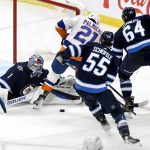 
              Winnipeg Jets goaltender Eric Comrie (1) makes a save against New York Islanders' Kyle Palmieri (21) during the third period of NHL hockey game action in Winnipeg, Manitoba, Saturday, Nov. 6, 2021. (Fred Greenslade/The Canadian Press via AP)
            