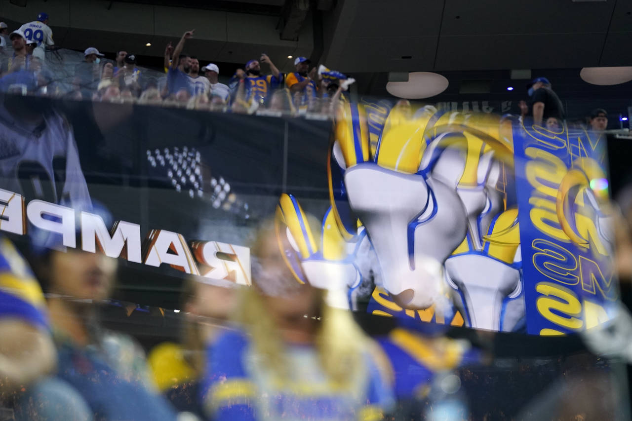 FILE - Fans are seen behind logos from the Los Angeles Rams at SoFi stadium during the first half o...