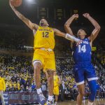 
              Michigan guard DeVante' Jones (12) makes a layup while defended by Seton Hall guard Jared Rhoden (14) during the second half of an NCAA college basketball game in Ann Arbor, Mich., Tuesday, Nov. 16, 2021. (AP Photo/Tony Ding)
            