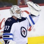 
              Winnipeg Jets goalie Connor Hellebuyck celebrates after the Jets scored an empty-net goal against the Calgary Flames during the third period of an NHL hockey game Saturday, Nov. 27, 2021, in Calgary, Alberta. (Larry MacDougal/The Canadian Press via AP)
            